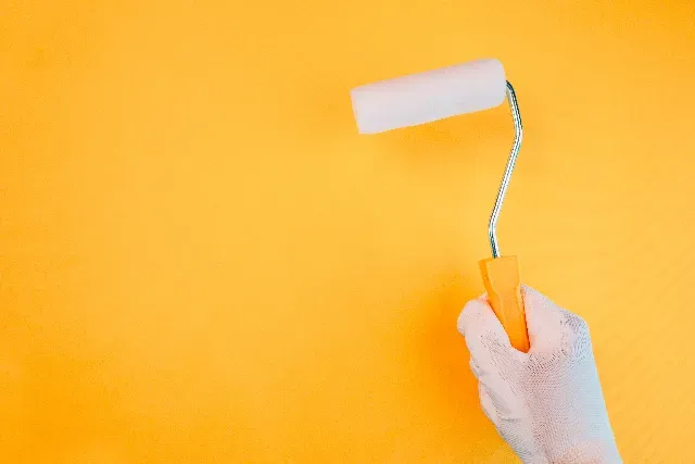 Aplicación de pintura con rodillo sobre una pared interior.